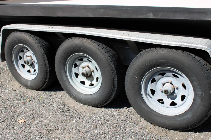 Slide: The Image of Triple-axle trailer wheels for 2008 Edgewater 318CC boat on gravel surface. - 6