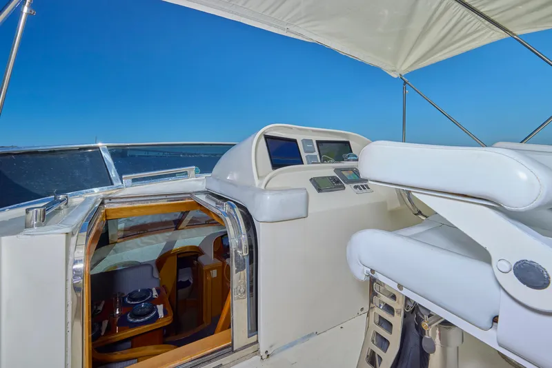 Slide: The Image of 2003 McKinna 58 Pilothouse yacht helm with white seating and open cabin view. - 12