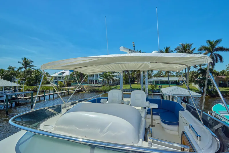 Slide: The Image of 2003 McKinna 58 Pilothouse yacht with canopy, docked near palm trees and waterfront homes. - 16