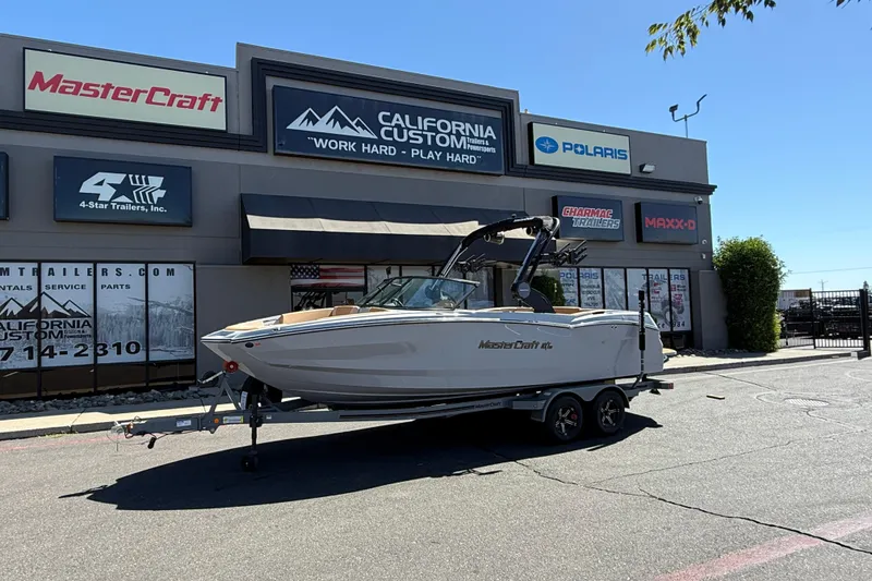 The Image of 2025 MasterCraft NXT23 boat on trailer outside California Custom dealership. - 0