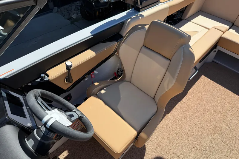 Slide: The Image of 2025 MasterCraft NXT23 boat interior with tan seating and modern steering wheel. - 16