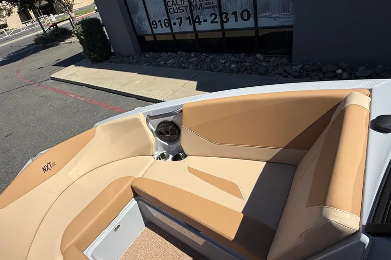 Slide: The Image of 2025 MasterCraft NXT23 boat interior with tan seating and cup holders. - 27