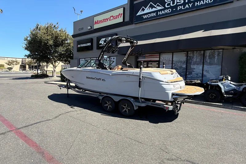 Slide: The Image of 2025 MasterCraft NXT23 boat on trailer outside dealership, sunny day. - 5