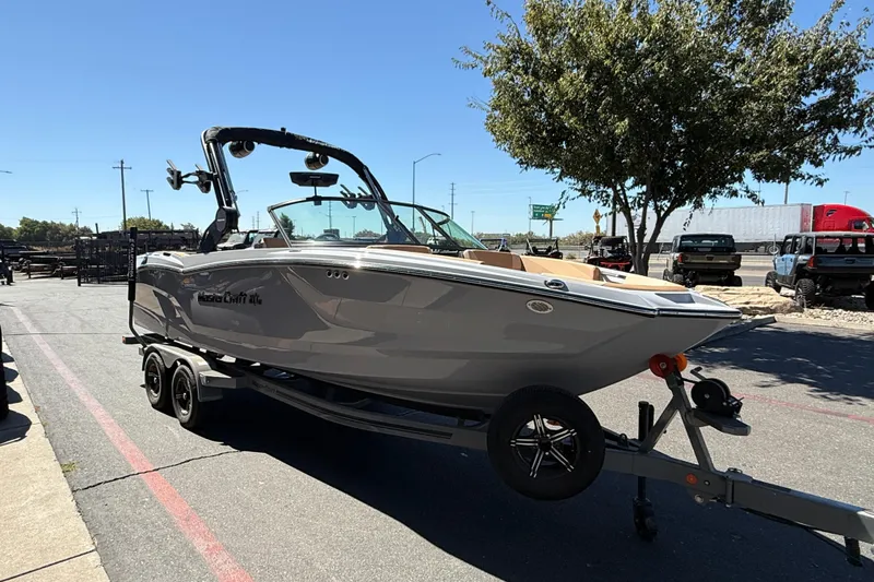 Slide: The Image of 2025 MasterCraft NXT23 boat on trailer, parked outdoors under clear blue sky. - 8