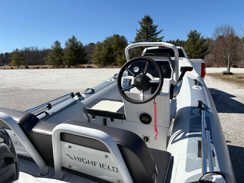 Slide: The Image of 2023 Highfield Sport 360 boat with steering wheel, parked outdoors on a sunny day. - 12