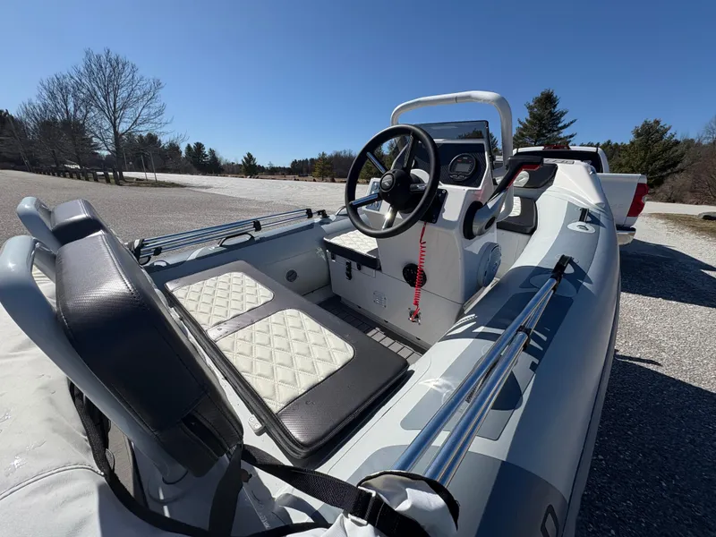 Slide: The Image of 2023 Highfield Sport 360 boat interior with steering wheel and seating, parked outdoors. - 13