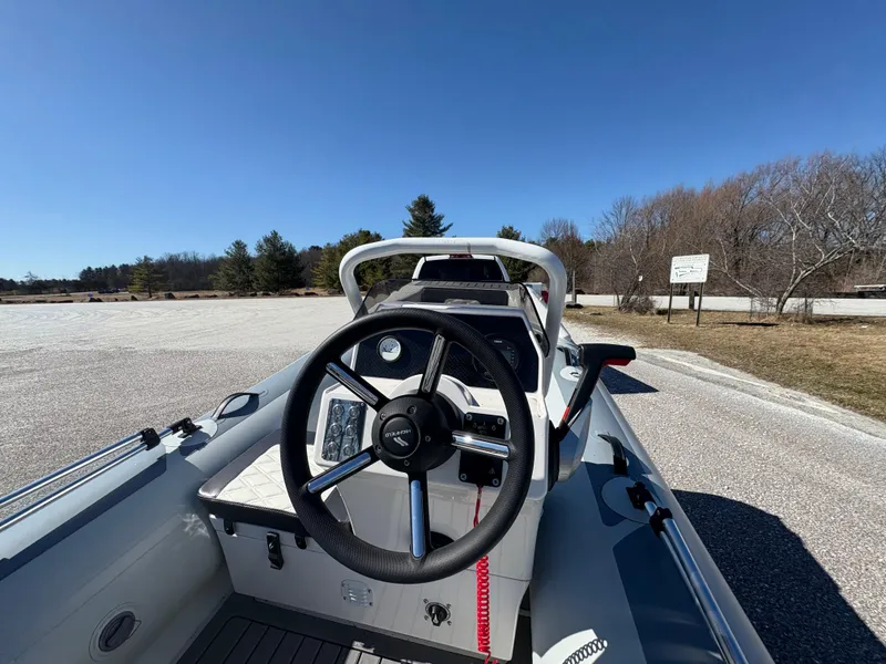 Slide: The Image of 2023 Highfield Sport 360 boat dashboard with steering wheel, parked outdoors under clear blue sky. - 17
