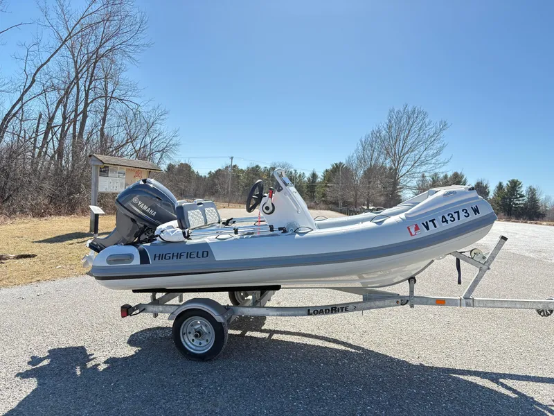 Slide: The Image of 2023 Highfield Sport 360 boat on trailer, parked outdoors on a sunny day. - 2