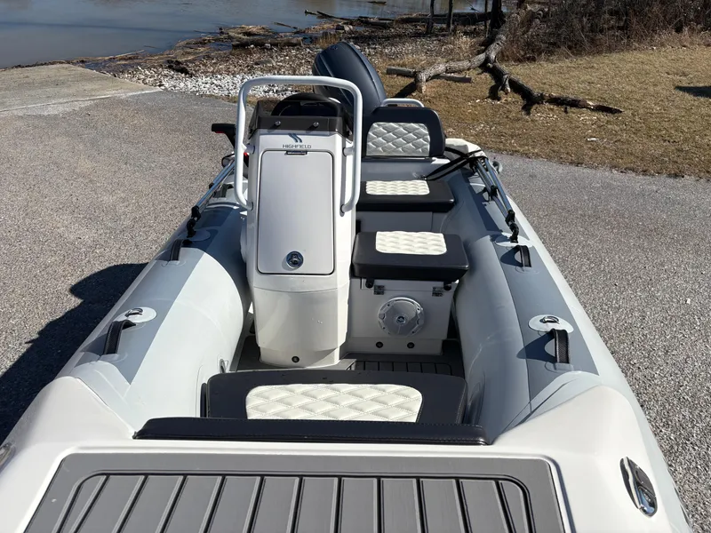 Slide: The Image of 2023 Highfield Sport 360 boat with sleek seating and console, docked near a shoreline. - 9