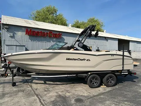 Slide: The Image of 2025 MasterCraft NXT23 boat on trailer outside MasterCraft building. - 1