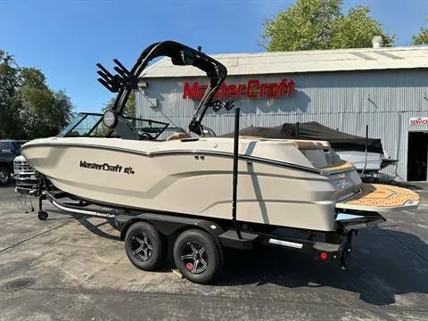 Slide: The Image of 2025 MasterCraft NXT23 boat on trailer, parked outside dealership. - 2