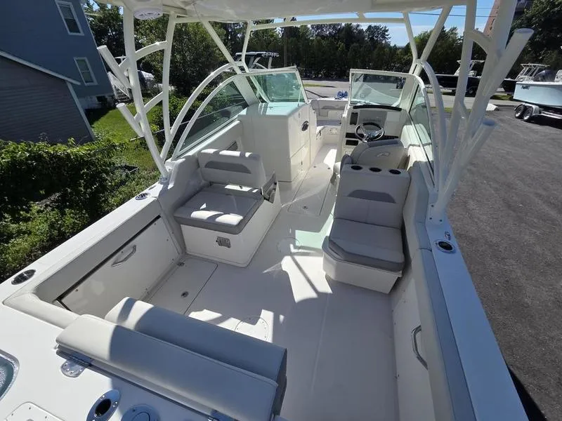 Slide: The Image of 2025 Sailfish 245 DC boat interior with seating and steering wheel, parked outdoors. - 11