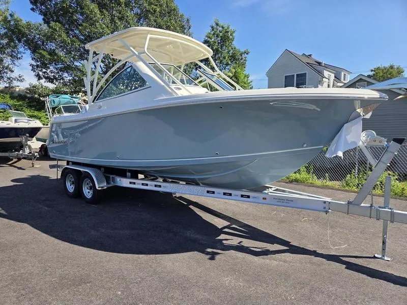 Slide: The Image of 2025 Sailfish 245 DC boat on trailer, parked outdoors, with trees and houses in the background. - 3