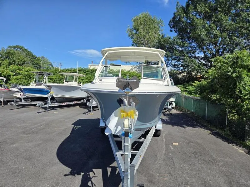Slide: The Image of 2025 Sailfish 245 DC boat on trailer, parked outdoors under clear blue sky. - 6
