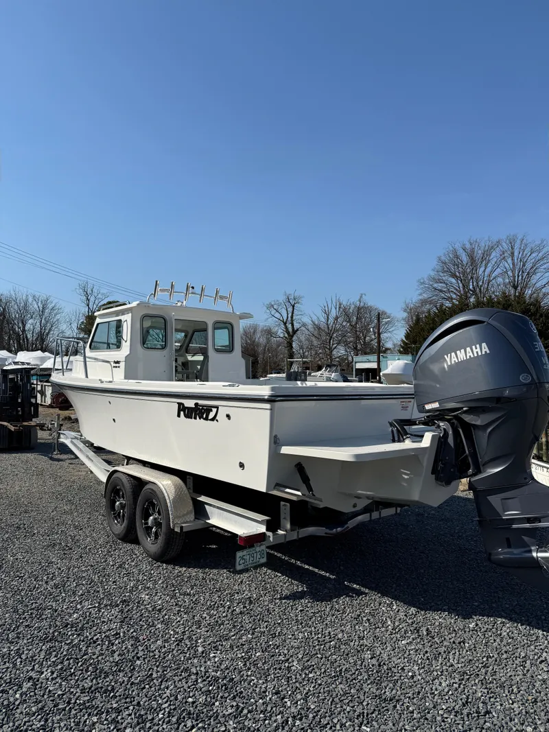Slide: The Image of 2025 Parker 2420 Sport Cabin boat with Yamaha engine on a trailer, parked outdoors. - 1