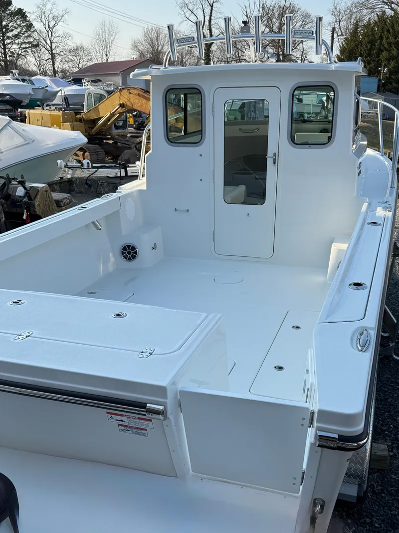 Slide: The Image of 2025 Parker 2420 Sport Cabin boat with spacious deck and cabin, docked outdoors. - 3