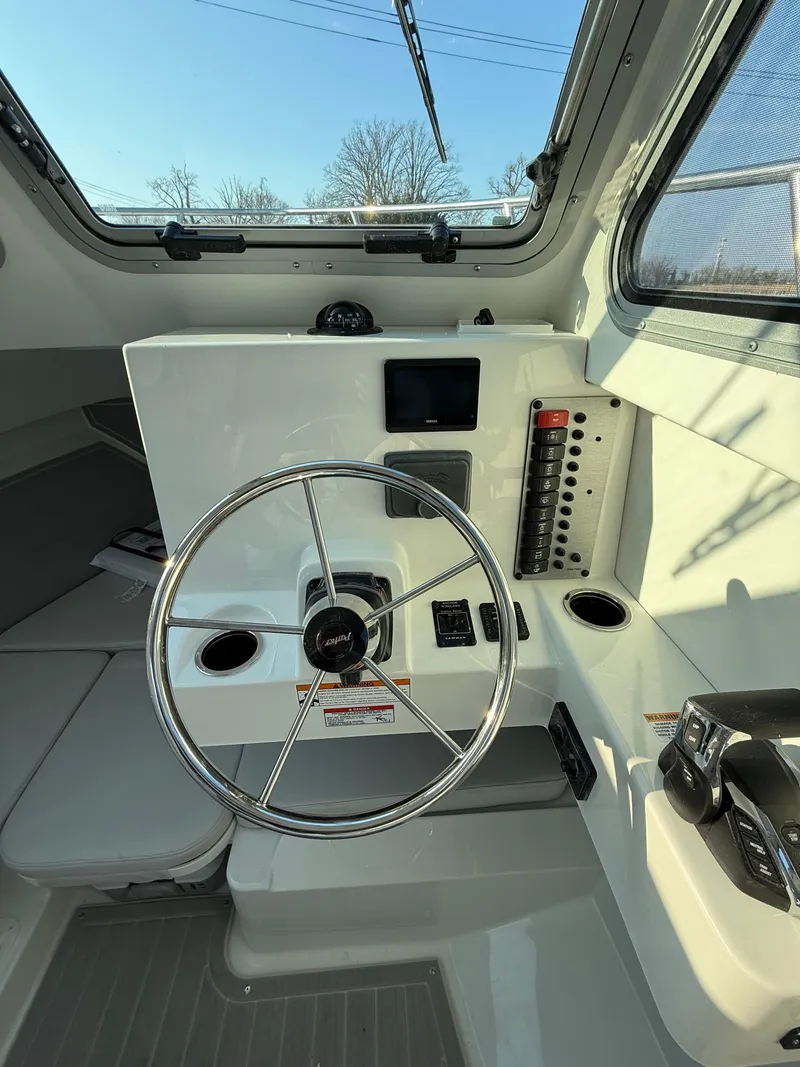 Slide: The Image of 2025 Parker 2420 Sport Cabin boat interior with steering wheel and control panel. - 8
