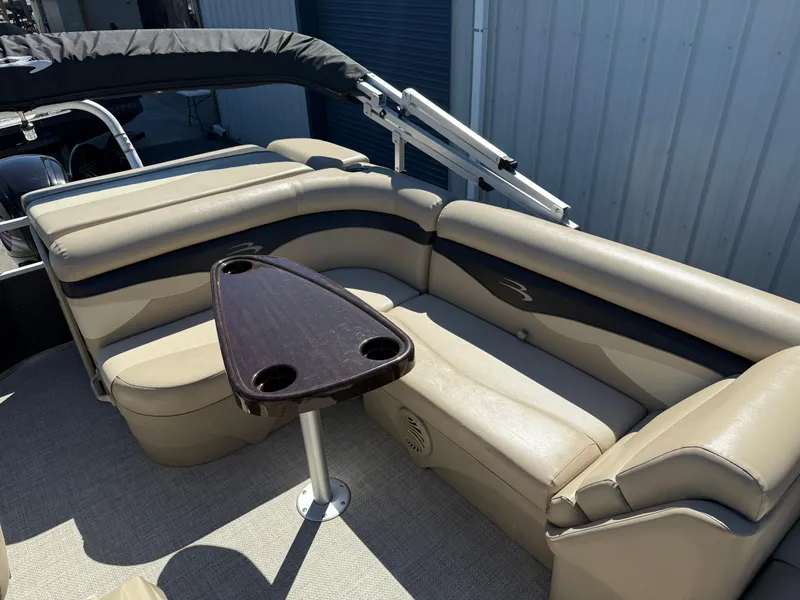 Slide: The Image of 2015 Bennington SLMX boat interior with beige seating and a small table. - 8