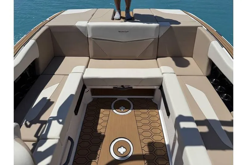 Slide: The Image of 2025 MasterCraft NXT22 boat interior with beige seating and teak-style flooring on water. - 5