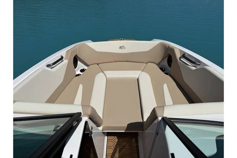 Slide: The Image of 2025 MasterCraft NXT22 boat interior with beige seating, on clear blue water. - 7