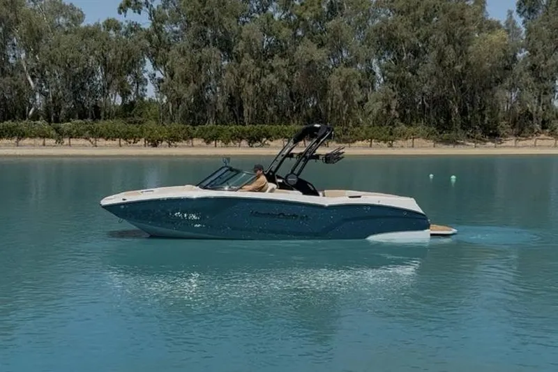 Slide: The Image of 2025 MasterCraft NXT22 boat on a serene lake with trees in the background. - 8