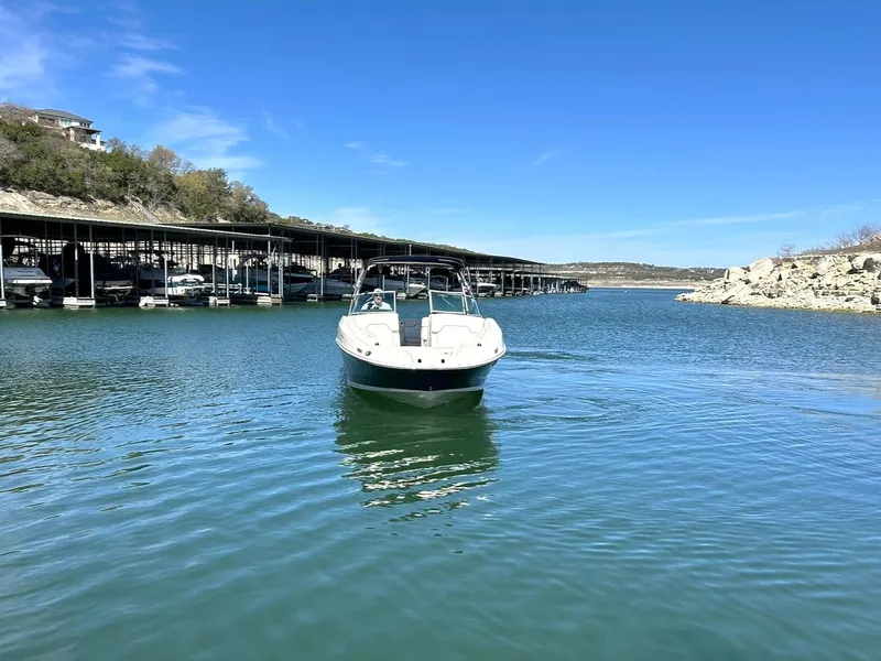 Slide: The Image of 2008 Sea Ray 290 Sundeck boat on calm water near marina and rocky shoreline. - 10