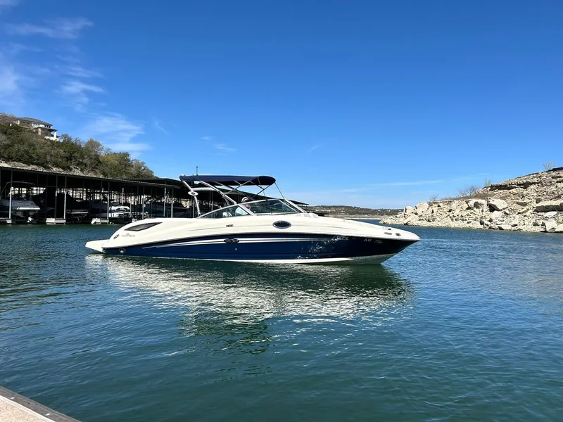 Slide: The Image of 2008 Sea Ray 290 Sundeck boat on a serene lake under a clear blue sky. - 13