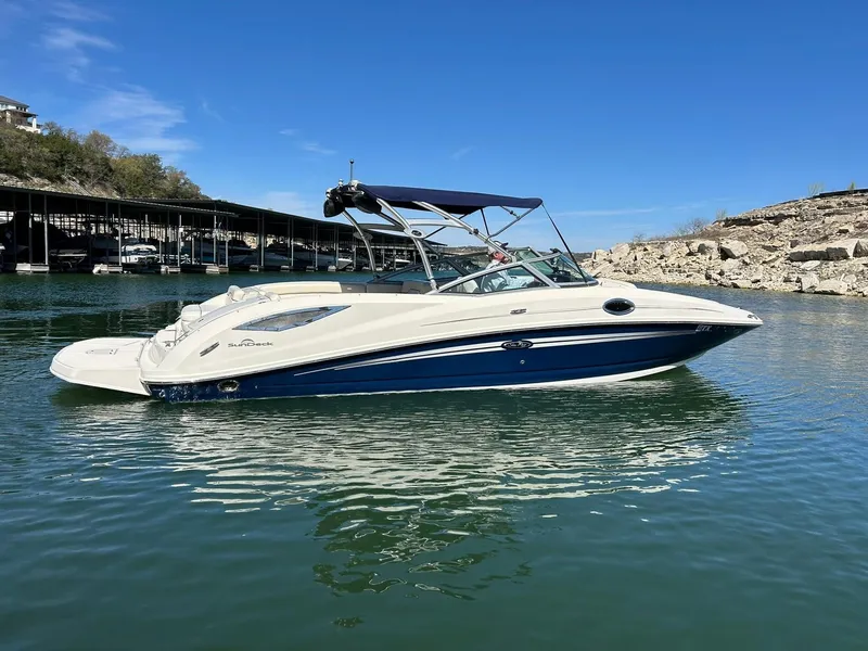 Slide: The Image of 2008 Sea Ray 290 Sundeck boat on calm water, clear blue sky background. - 16
