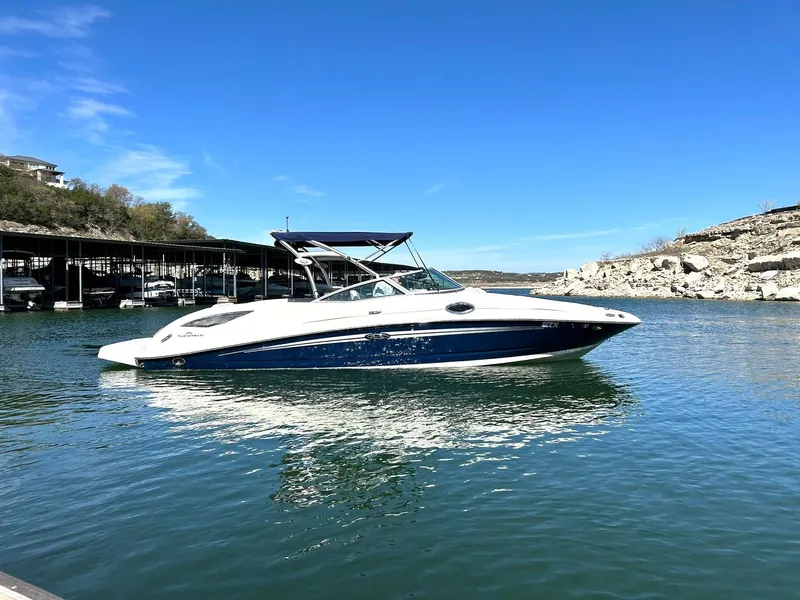 Slide: The Image of 2008 Sea Ray 290 Sundeck boat on calm water under clear blue sky. - 2