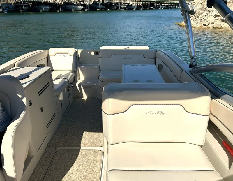 Slide: The Image of 2008 Sea Ray 290 Sundeck boat interior with spacious seating and table, docked by the water. - 31