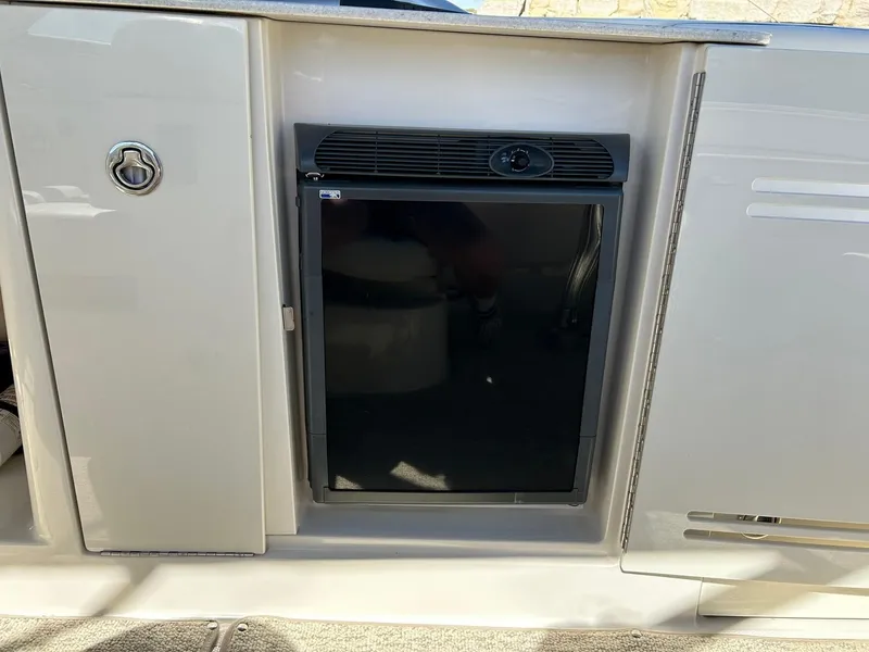 Slide: The Image of 2008 Sea Ray 290 Sundeck interior with built-in mini fridge and storage cabinets. - 34