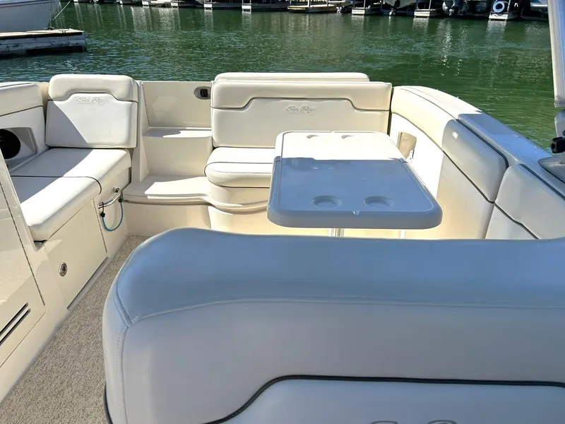 Slide: The Image of 2008 Sea Ray 290 Sundeck interior with white seating and table, docked by the water. - 4