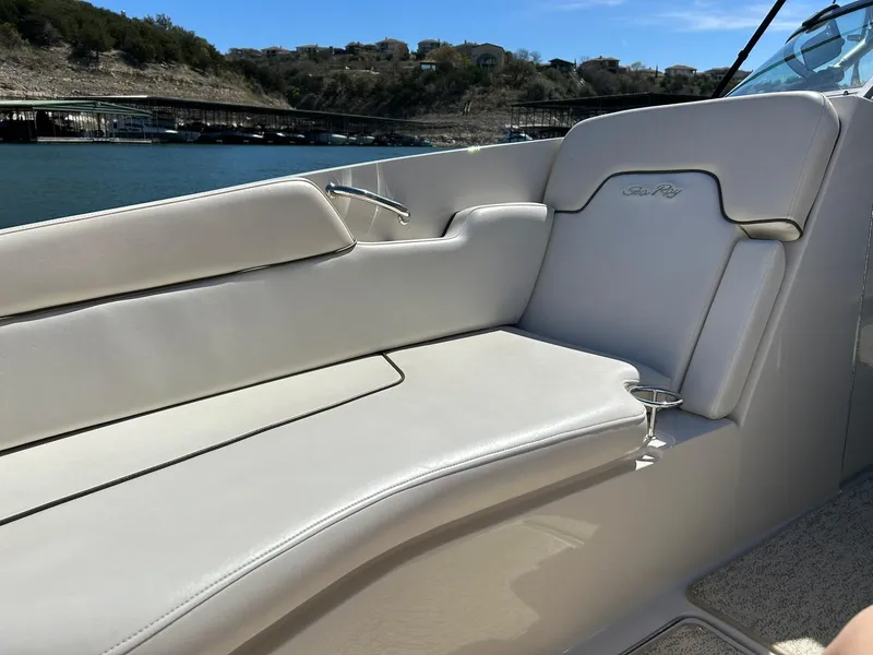 Slide: The Image of 2008 Sea Ray 290 Sundeck boat interior with beige seating, near a scenic waterfront. - 47