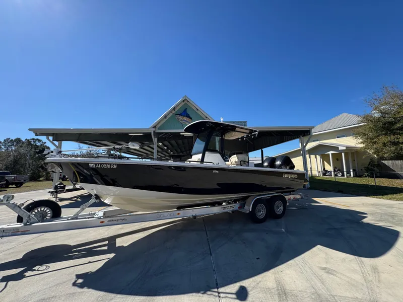 Slide: The Image of 2017 Everglades 273 Center Console boat on trailer, parked in driveway under clear blue sky. - 3