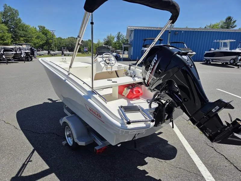 Slide: The Image of 2025 Boston Whaler 130 Super Sport boat with Mercury engine, parked outdoors. - 10
