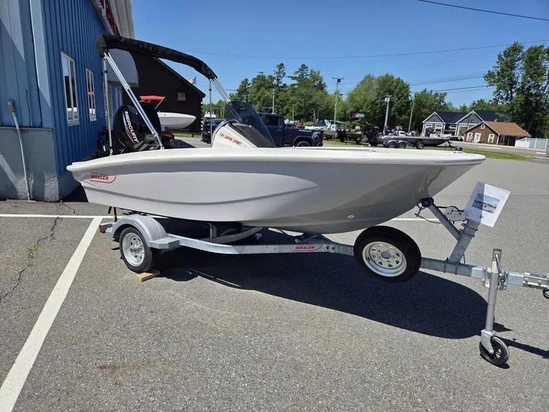 Slide: The Image of 2025 Boston Whaler 130 Super Sport boat on trailer, parked outdoors. - 4