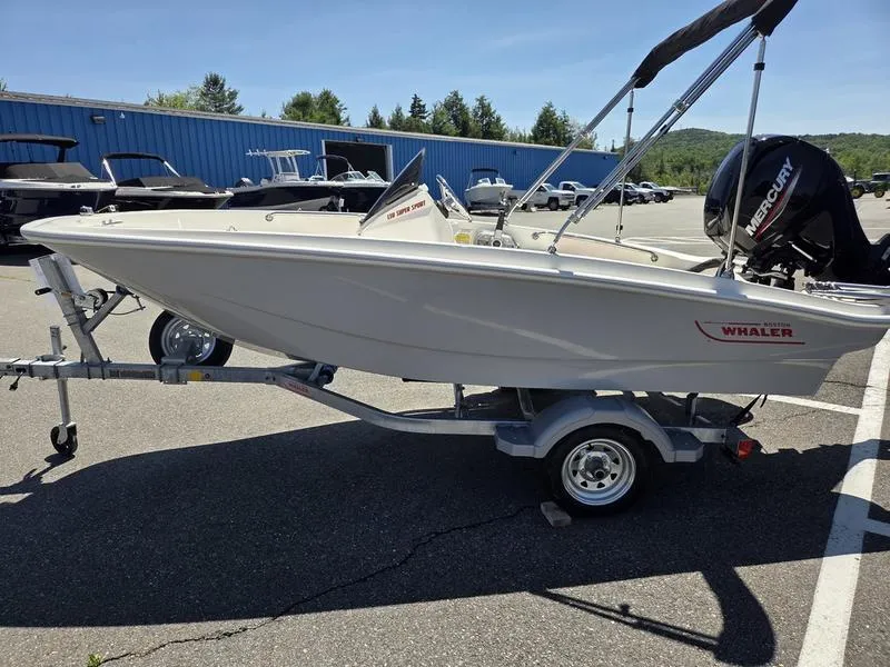 Slide: The Image of 2025 Boston Whaler 130 Super Sport boat on trailer in parking lot. - 7