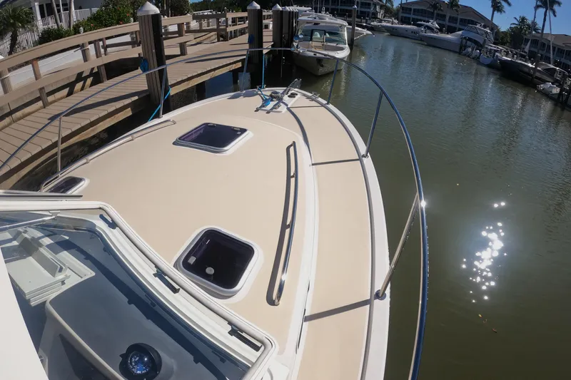 Slide: The Image of 2018 MJM 35z boat docked in a sunny marina, showcasing sleek design and spacious deck. - 11