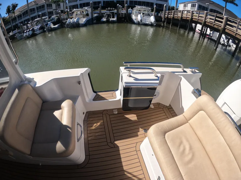 Slide: The Image of 2018 MJM 35z boat interior with tan seating and wooden deck, docked at marina. - 16
