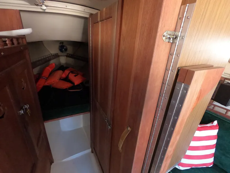 Slide: The Image of Interior of 1983 Catalina 27 sailboat with wooden cabinets and life jackets. - 12
