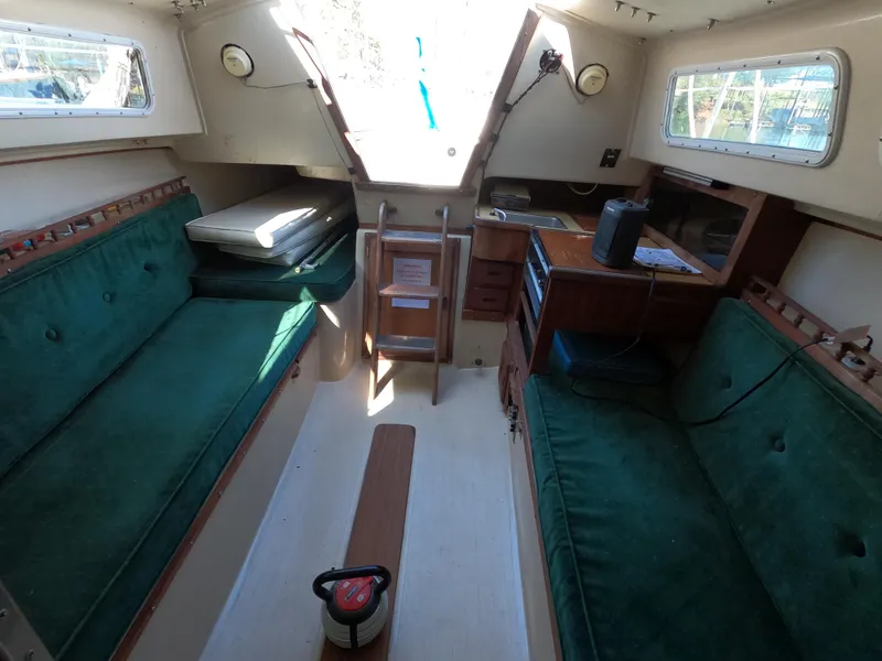 Slide: The Image of Interior of a 1983 Catalina 27 sailboat with green cushioned seating and wooden accents. - 14