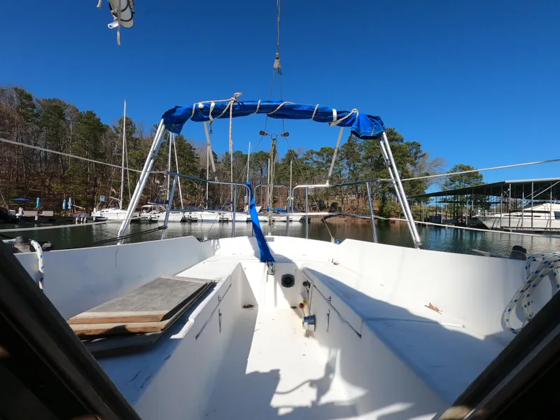 Slide: The Image of 1983 Catalina 27 sailboat cockpit with blue canopy, docked in a serene marina setting. - 16
