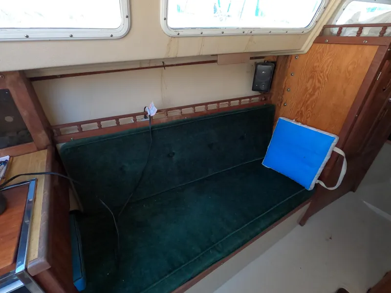 Slide: The Image of Interior of a 1983 Catalina 27 sailboat with green cushioned seating and wooden accents. - 9