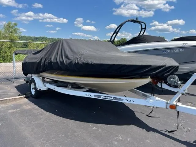 Slide: The Image of 2001 Wellcraft 175SS boat covered on trailer, parked outdoors under a blue sky. - 9
