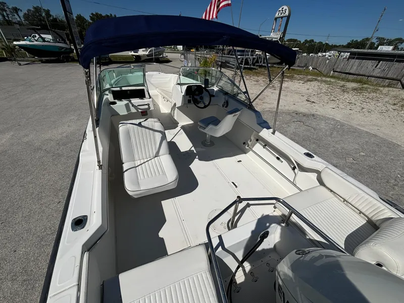 Slide: The Image of 1999 Boston Whaler 20 Ventura Bowrider with seating, canopy, and steering wheel in a sunny outdoor setting. - 17