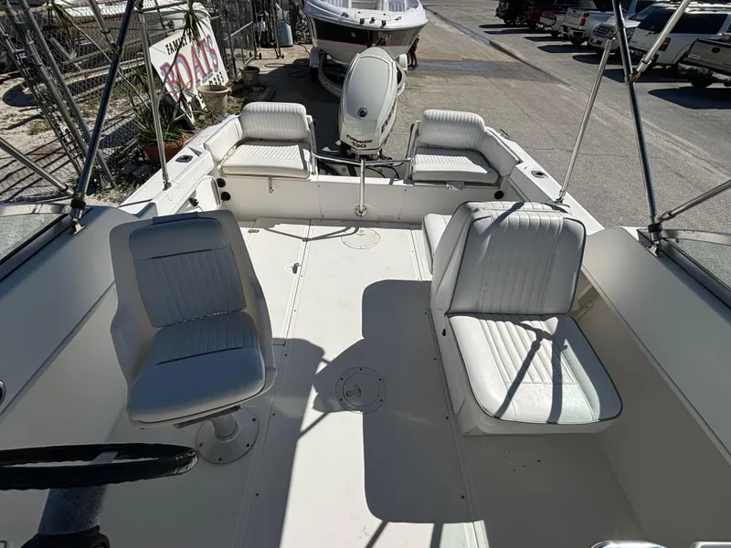 Slide: The Image of 1999 Boston Whaler 20 Ventura Bowrider with white seating and steering wheel, docked outdoors. - 27