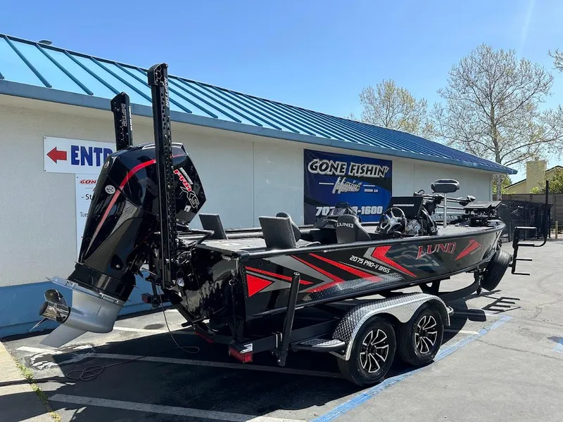 Slide: The Image of 2025 Lund 2075 Pro-V Bass XS boat on trailer outside a fishing shop. - 6
