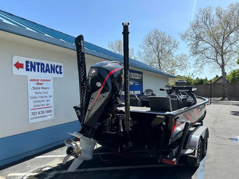 Slide: The Image of 2025 Lund 2075 Pro-V Bass XS boat parked near a building entrance. - 7