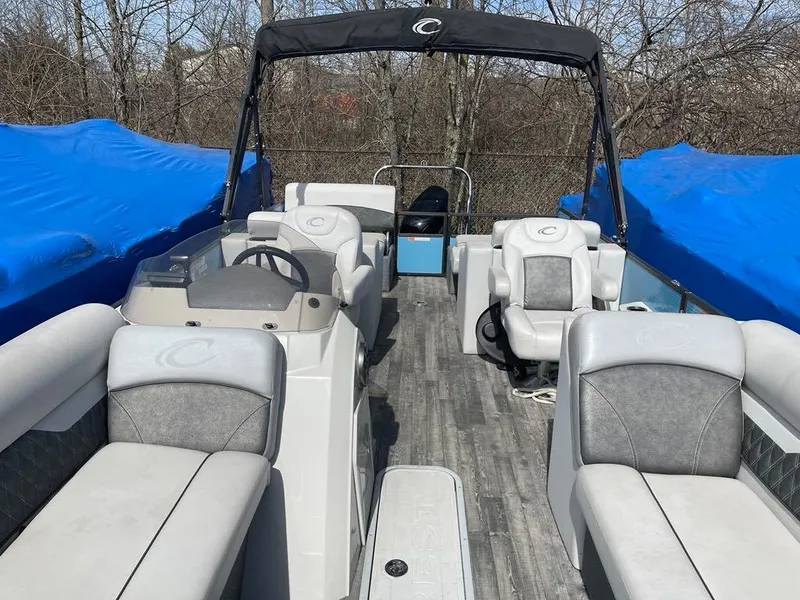 Slide: The Image of 2019 Crest Classic Platinum 220 SLRC pontoon boat with gray seating and canopy, parked outdoors. - 3