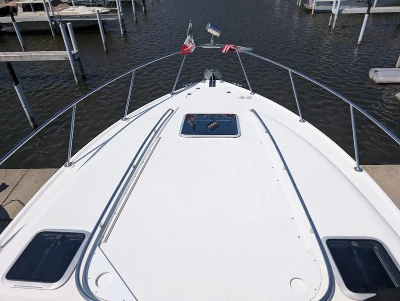 Slide: The Image of 2006 Chaparral 310 Signature boat bow view at dock, featuring sleek design and flags. - 14